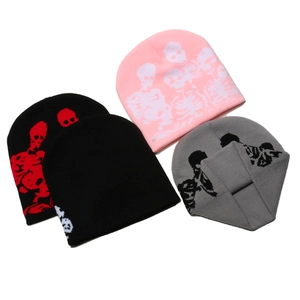 Flat lay of knit beanies in pink, black, and grey featuring skull and bone patterns