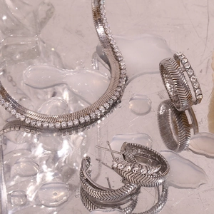Detailed view of stainless steel jewelry set with fishtone pattern and white rhinestones