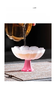 Macro shot of a pink glazed lotus-shaped glass goblet showing tea pouring motion