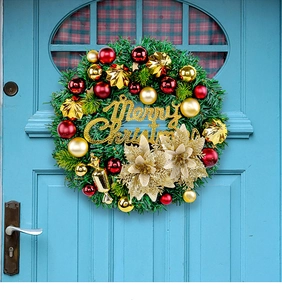 Close-up of Christmas wreath with gold balls and Merry Christmas sign on blue door