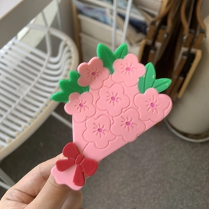 Dettaglio di un fermaglio per capelli con bouquet di fiori rosa in acetato e fiocco rosso