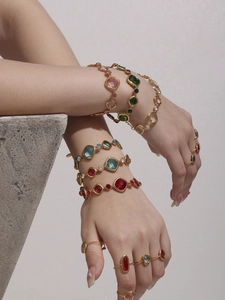 Details von bunten Glasstein-Armbändern und Ringen mit Vergoldung an einem Model