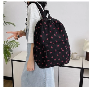 Detail of corduroy backpack featuring red strawberry pattern and dual zipper closure