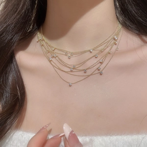 Close-up of layered gold ball chain necklace with sparkling zircon stones on model