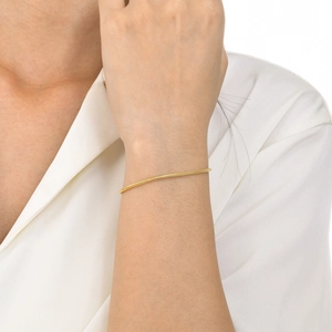 Close-up of minimalist gold snake bone chain bracelet worn on a woman's wrist
