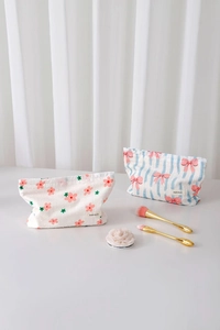 Dettaglio di pochette cosmetiche in cotone floreale con fiocco rosa ed etichetta H&R BAG