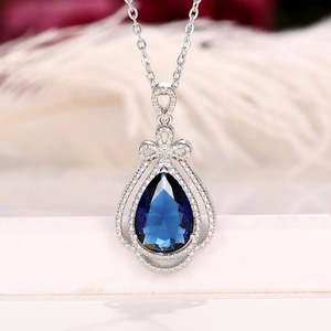 Detail of elegant pear-shaped blue sapphire pendant with a delicate silver bow knot