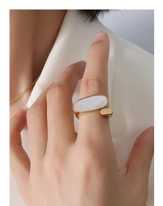 Gros plan d'une bague dorée 18 carats avec nacre blanche ovale portée par un mannequin
