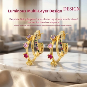 Detail of 18K gold-plated C-shaped earrings with multi-colored zircons on marble
