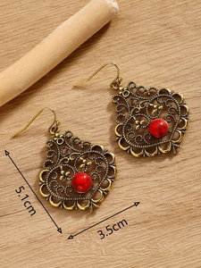 Detailed size view of bohemian antique gold earrings with red stone inlay on wood