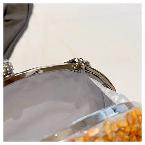 Detailed close-up of the silver metal clasp and gold sequined texture on a party clutch