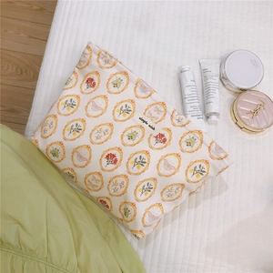 Detail of floral canvas makeup bag with vintage frame patterns on a soft bed background
