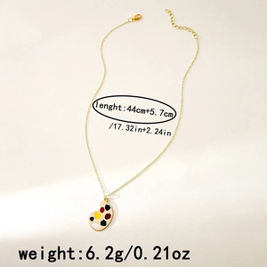 Detailed shot of golden palette pendant necklace with colorful enamel on white texture
