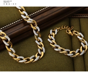 Macro shot of gold-plated Cuban link jewelry set with pave-set crystals on green velvet