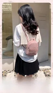 Pink mini backpack with monogram pattern shown on a female model outdoors