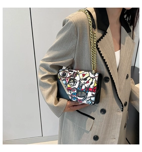 Detail of pop art print crossbody bag with gold chain strap on a beige suit model
