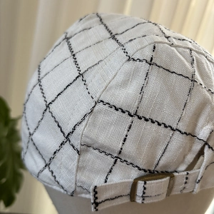 Detail of the adjustable bronze metal buckle and plaid linen fabric on a flat cap