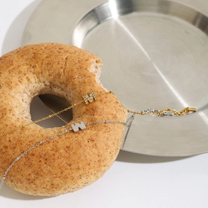 Detail view of gold and silver titanium bracelets with M letter charm and zircon stones
