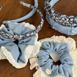 Detail showing blue floral headband and lace hair scrunchie on dark wood surface