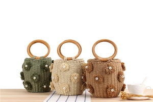 Detail of handmade bucket bags with woven flowers, pearl accents and round wood handles