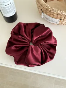Detail of burgundy satin oversized scrunchie with silky texture and elegant folds