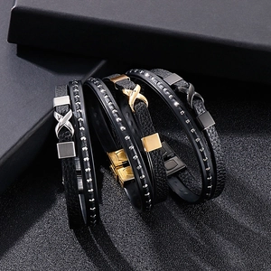 Detail of layered black leather bracelets with infinity symbol in gold, silver, and black