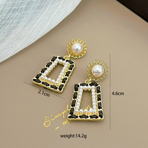 Detail view of retro gold earrings with pearls and black leather woven frames