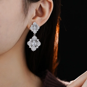 Gros plan sur un mannequin portant des boucles d'oreilles fleur en argent et zircon