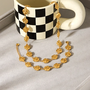 Détail d'un ensemble collier et bracelet rose dorée drapé sur un mug en damier
