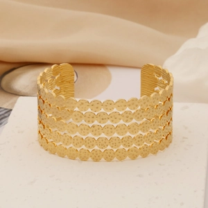 Macro detail of golden open cuff bracelet featuring hammered texture and hollow layers