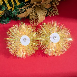 Detail von Weihnachts-Glitzer-Ohrringen mit goldenen Pompons auf rotem Hintergrund
