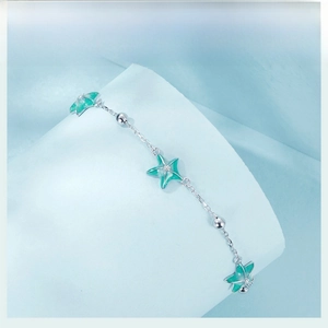 Macro view of silver starfishes on an elegant bracelet with light green gradient details