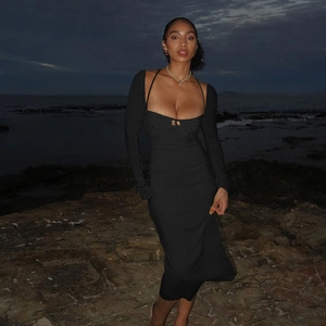 Détail d'une robe moulante noire à manches longues et décolleté licou au bord de mer