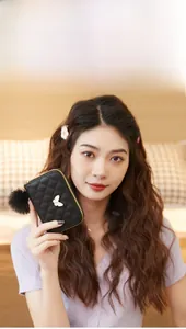 Close-up of black quilted leather coin purse with golden butterfly and pompom detail