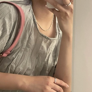 Close-up of minimalist 925 sterling silver beaded necklace and ring worn by a model