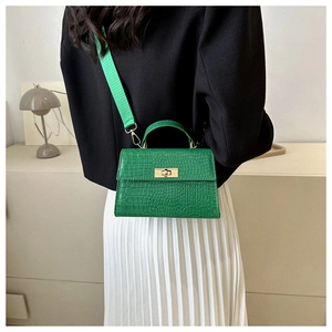 Detail of green crocodile textured crossbody bag with gold hardware and wide strap