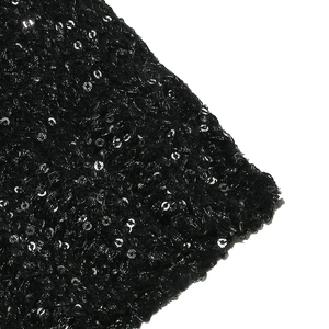 Dettaglio macro di paillettes nere luccicanti su tessuto a maglia di alta fattura