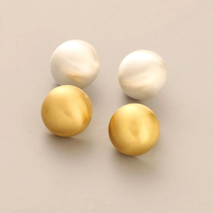 Macro detail of matte brushed texture on gold and silver dome stud earrings set