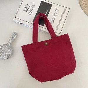 Minimalist burgundy canvas tote bag with metal snap button shown from top view