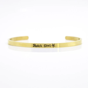 Close-up of 4mm gold stainless steel cuff bracelet with Beach Soul and star engraving