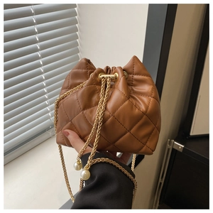 Close-up of brown quilted bucket bag featuring gold chains and white pearl charms