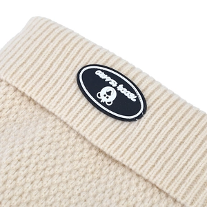 Macro detail of creamy white knit texture with a Teddy Island bear rubber patch