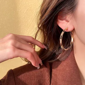 Chic oversized gold hoop earrings with sparkling diamonds on a stylish model