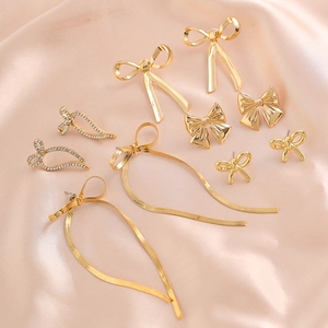 Macro view of golden bow earrings set with rhinestones and snake chain tassels