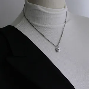 Titanium steel rivet lock pendant necklace in silver finish on a chic black blazer