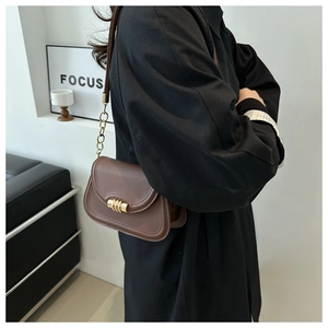 Detail of dark brown saddle bag featuring vintage gold hardware and chain strap