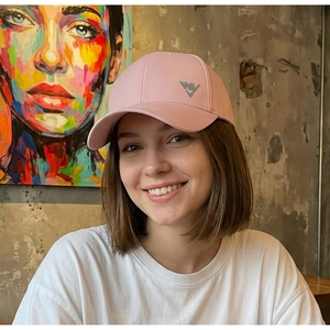 Young woman wearing a pink sun protection baseball cap in a casual cafe setting