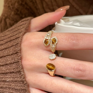 Detailed close-up of adjustable gold ring set with tiger eye stones and zircons