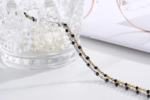 Detail of dual-tone gold and silver metal eyeglass chain with small black decorative beads