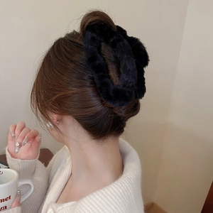 Detail of a black plush hair claw clip worn on a bun hairstyle with a soft aesthetic